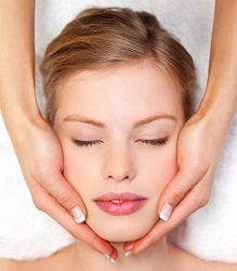 Closeup of human hands massaging a young pretty woman's face