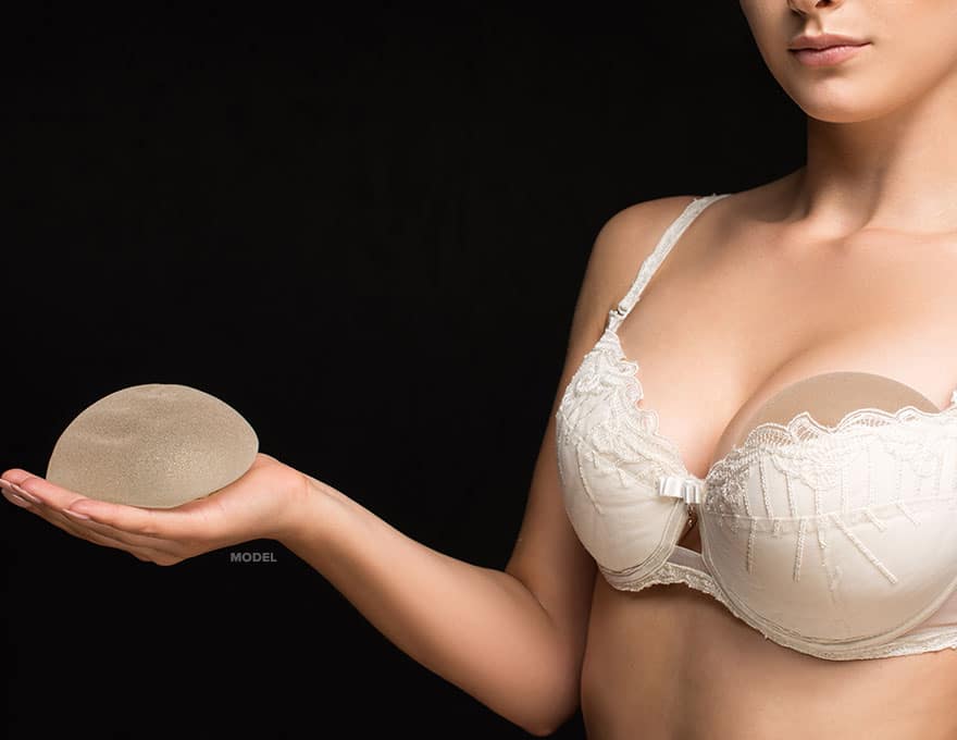Woman with white bra holding implants