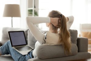 Woman Relaxing On Couch With Computer On Her Lap