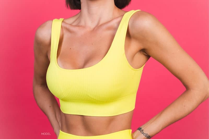 Woman wearing a yellow sports bra against a pink background