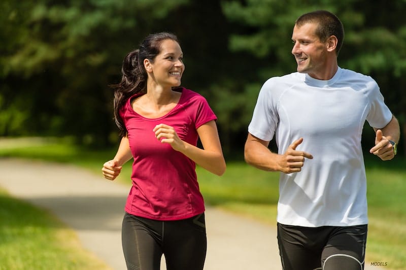 Fit man and woman jogging while smiling at each other